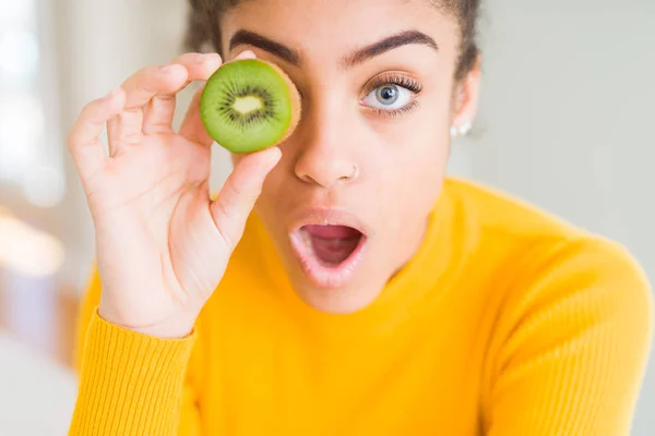 Young African American Girl Eating Green Kiwi Scared Shock Surprise — Stock Photo, Image