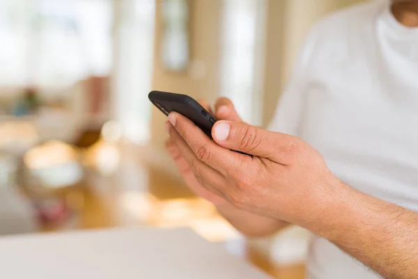 Gros plan des mains de l'homme d'âge moyen en utilisant un smartphone à la maison — Photo