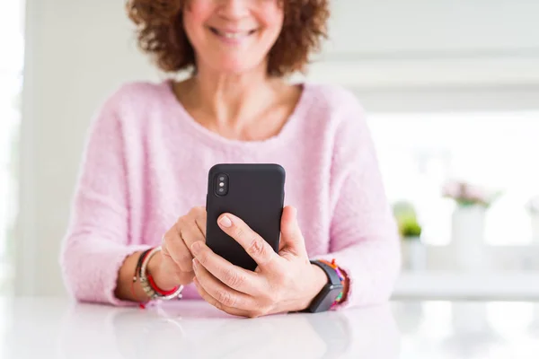 Primer plano de la mujer mayor utilizando el teléfono inteligente sobre la mesa blanca smili —  Fotos de Stock