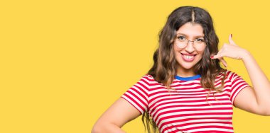 İşin gülümseyen gözlüklü genç güzel kadın telefon hareketi ile el ve parmak telefonda konuşuyor gibi. Kavramları iletişim.