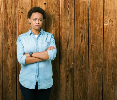 İzole arka plan üzerinde genç güzel Afrikalı Amerikalı kadın şüpheci ve sinir, kesişmiş kollar ile yüz üzerinde ifade onaylamıyor. Negatif kişi.