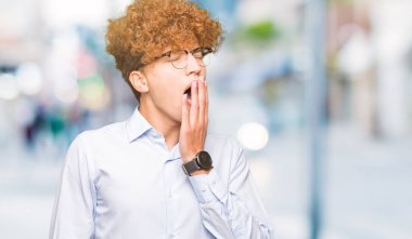 Afro giyen gözlük sıkılmış esneme ile genç yakışıklı iş adamı el ağzıyla kapsayan yorgun. Restless ve uyku hali.