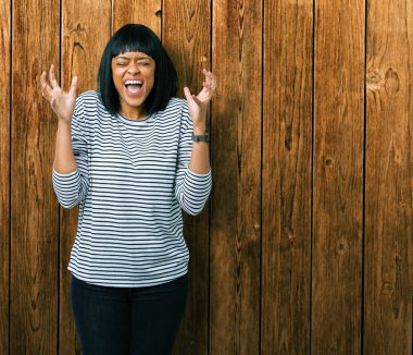 Üzerinde çizgili süveter giyen güzel genç Afro-Amerikan kadın deli ve çığlık kaldırdı ve kapalı gözleri heyecanlı silah ile başarı için deli kutluyor arka plan izole. Kazanan kavramı