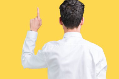 Genç yakışıklı iş adam gözlük izole üzerinden geriye doğru arkasında parmak eliyle işaret Posing arka plan
