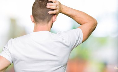 Yakışıklı adam geriye doğru elle kafasında şüphe hakkında düşünme casual beyaz t-shirt giyen
