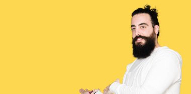 Uzun saçlı ve sakal giyen sportif Sweatshirt ile genç hipster adam açık el ile gülümseyen doğal girmek için davet