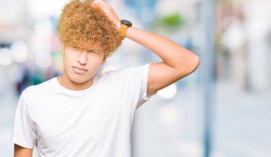 Casual beyaz t-shirt giyen afro saçlı yakışıklı delikanlı yanıltır ve soru hakkında merak ediyorum. Şüphe, kafasına el ile düşünme ile belirsiz. Dalgın kavramı.