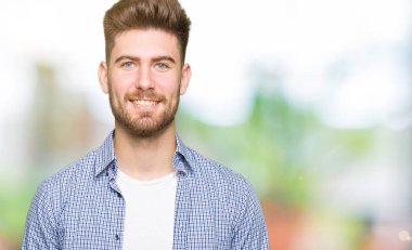 Yüzünde mutlu ve güzel bir gülümseme ile rahat gömlek giymiş genç yakışıklı sarışın adam. Şanslı kişi.