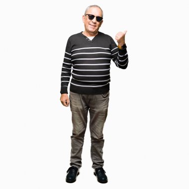 Kış kazak ve seyir ve başparmak yanında yukarıyı mutlu yüz ile gülümseyen güneş gözlüğü takan yakışıklı komuta sizde.