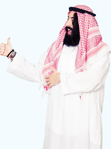 笑顔長い髪を誇り 伝統的なクーフィーヤ スカーフ着用のアラビアン ビジネス男の親指側にジェスチャーを — ストック写真
