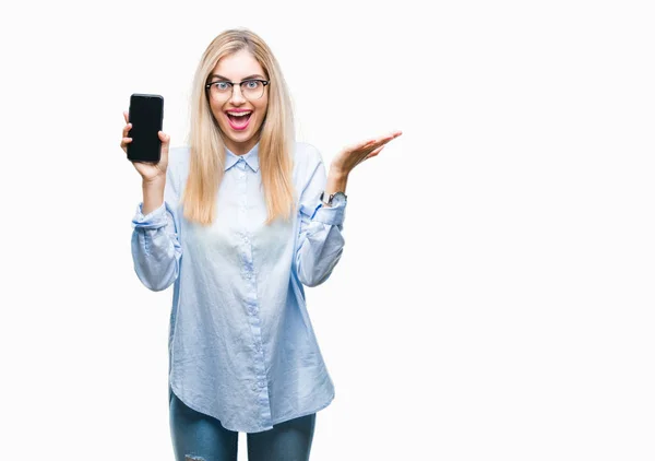 年轻美丽的金发女郎商业妇女显示屏幕的智能手机在孤立的背景非常高兴和兴奋 赢家表达庆祝胜利尖叫与大微笑和举手 — 图库照片