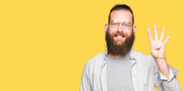 Genç sarışın adam gösteren gözlük giyen ve parmak sayısı dört ile işaret ederken emin ve mutlu gülümseyen.