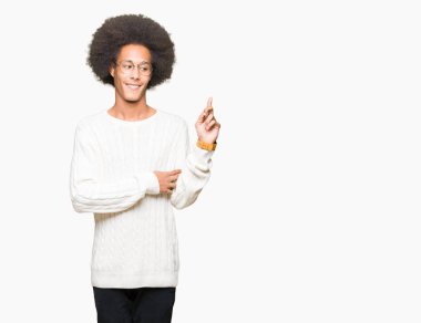 Kameraya bakarak yan el ve parmak ile işaret eden genç Afro-Amerikan adam afro saçlı gözlüklü kocaman bir gülümseme ile yüzünde,.