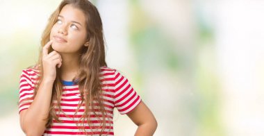 Çene düşünme hakkında soru, dalgın ifade üzerine el ile izole arka plan üzerinde tişört giyen genç güzel esmer kadın çizgili. Düşünceli yüzüyle gülümsüyor. Şüphe kavramı.