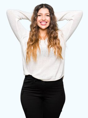 Beyaz kazak giyen genç güzel kadın Rahatlatıcı ve kollar ve eller baş ve boyun arkasında germe, mutlu gülümseyen