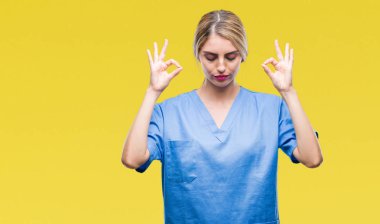 Genç güzel sarışın doktor cerrah hemşire kadın izole arka plan üzerinde dinlenmek ve gülümseyen gözlerle parmak ile meditasyon jest yapıyor kapalı. Yoga kavramı.