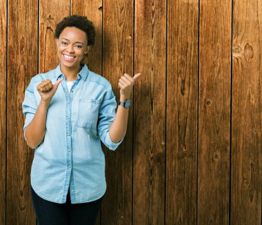 Izole arka plan üzerinde Genç güzel afro-amerikan kadın el ve başparmak yukarı arka işaret, kendinden emin gülümseyerek