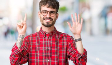 Gösterilen arka plan üzerinde gözlük takan genç yakışıklı adam izole ve parmakları ile işaret kendinden emin ve mutlu gülümseyerek süre 6 numara.