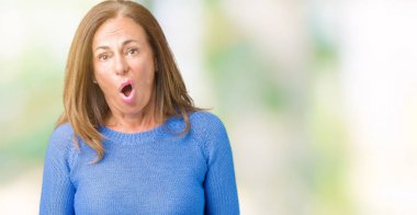 Orta yaş şüpheci ve alaycı, şok karşısında arka plan üzerinde kış kazak giyen güzel kadın izole açık ağız ile şaşırttı