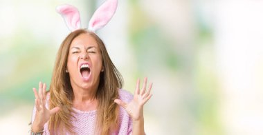 Paskalya tavşan kulakları üzerinde giyen orta yaş esmer kadın deli ve deli bağırarak ve agresif ifade ve silah kaldırdı bağırmaya arka izole. Hayal kırıklığı kavramı.