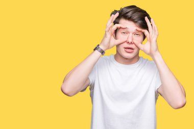 Parmaklarıyla, Uykulu ve sabah yorgunluk için yorgun gözlerini açmaya çalışırken izole arka plan üzerinde rahat beyaz t-shirt giyen genç yakışıklı adam