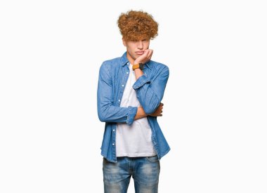 Afro saçlı kot ceket düşünme seyir giyen genç yakışıklı adam yorgun ve sıkılmış çapraz silah depresyon sorunları ile.