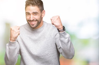 Üzerine tişört giyen genç yakışıklı adam arka plan çok mutlu ve heyecanlı kaldırdı, silah ile kazanan jest yapıyor gülümseyen ve başarı için çığlık izole. Kutlama kavramı.