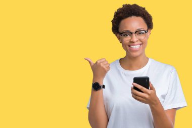 İşaret ve başparmak kadar mutlu yüz gülümseyen tarafı ile gösteren izole arka plan üzerinde akıllı telefon kullanan genç Afro-Amerikan kadın