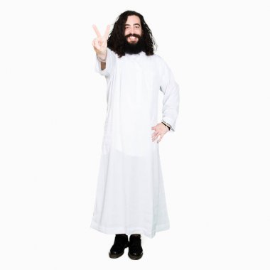 Adam Isa Mesih kostüm gösteren ve parmaklar iki numarası ile işaret giymiş iken emin ve mutlu gülümseyen.