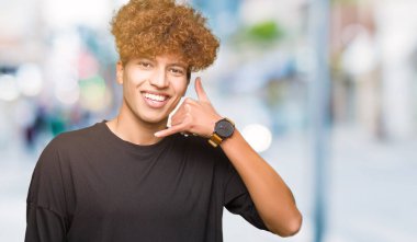 Siyah t-shirt giyen afro saçlı yakışıklı delikanlı gülümseyen el ve parmak telefonda konuşmak ile telefon jest yapıyor. Kavramları iletişim.