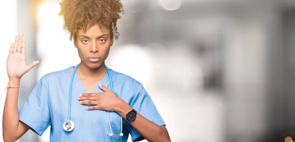 Young african american doctor woman over isolated background Swearing with hand on chest and open palm, making a loyalty promise oath