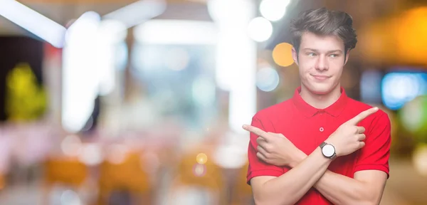 stock image Young handsome man wearing red t-shirt over isolated background Pointing to both sides with fingers, different direction disagree