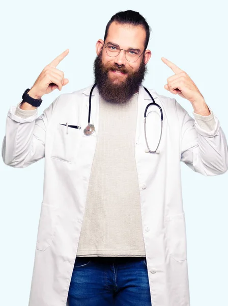 Joven Doctor Rubio Con Barba Usando Abrigo Médico Sonriendo Apuntando — Foto de Stock