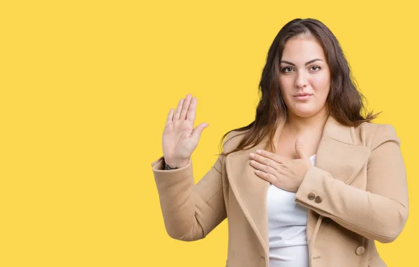 Beautiful plus size young woman wearing winter coat over isolated background Swearing with hand on chest and open palm, making a loyalty promise oath