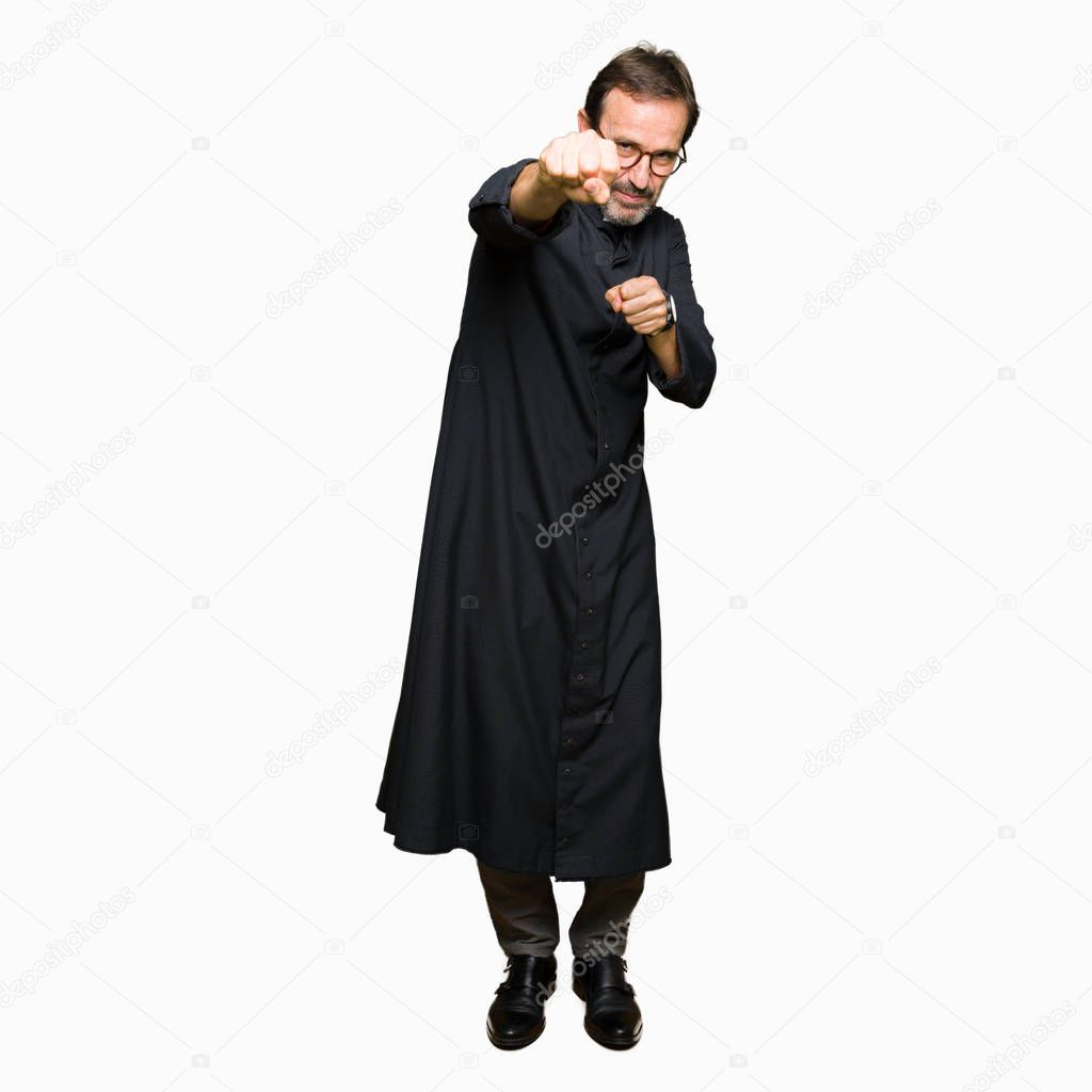 Middle age priest man wearing catholic robe Punching fist to fight, aggressive and angry attack, threat and violence