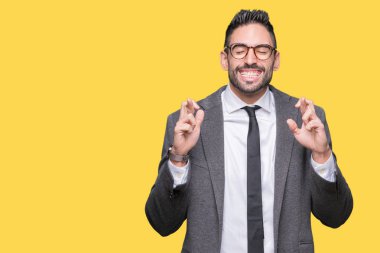 Genç yakışıklı iş adamı geçiş parmakları umut ve gözleri kapalı ile gülümseyen izole arka plan üzerinde. Şans ve batıl kavramı.