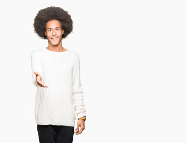 Afrikalı-Amerikalı genç afro saçlı tebrik ve konuksever dost sunan karşılıklı gülümseyen kış kazak giyiyor. Başarılı iş.