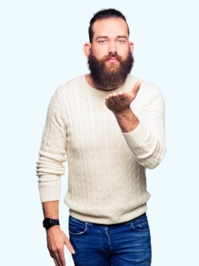 Bir öpücük el ile güzel ve seksi olmak hava üfleme kamera bakarak kış kazak giyen genç hipster adam. Aşk ifade.