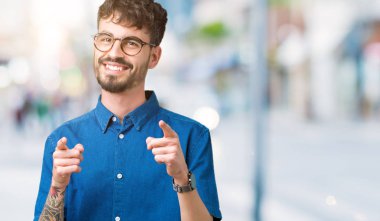 Fotoğraf makinesi ile mutlu ve komik yüz için parmakları işaret izole arka plan üzerinde gözlük takan yakışıklı delikanlı. İyi enerji ve vibes.
