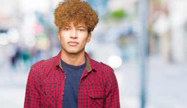 Yüzünde ciddi bir ifade ile ceket afro saçlı genç yakışıklı öğrenci adam. Basit ve doğal kameraya bakıyor.