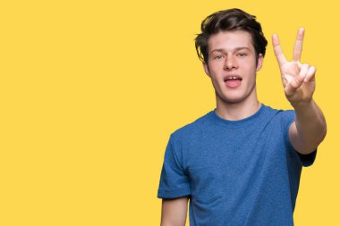 Yakışıklı delikanlı gösterilen ve parmakları ile işaret izole arka plan üzerinde mavi t-shirt giyen ikincisi ise kendinden emin ve mutlu gülümseyerek.