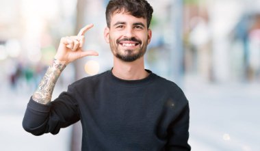 Yakışıklı genç gülümseyen izole arka plan ve süre seyir ve kamera boyutu işaret parmaklarıyla yapıyor el ile kendinden emin eller üzerinde. Ölçü kavramı.