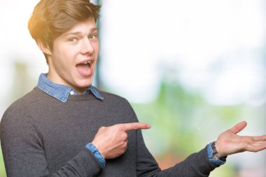 Genç yakışıklı zarif adam üzerinden hayran ve el ile sunulması ve parmak ile işaret ederken kameraya gülümseyen izole arka plan.