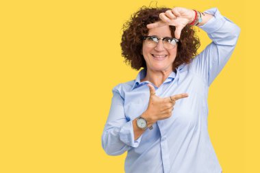 Güzel orta ager üst düzey businees kadın elle yapma çerçeve ve parmakları ile mutlu yüz gülümseyen izole arka plan üzerinde gözlük takıyorum. Yaratıcılık ve Fotoğrafçılık kavramı.