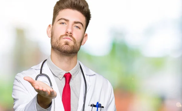 Young Handsome Doctor Man Wearing Medical Coat Looking Camera Blowing — Stock Photo, Image