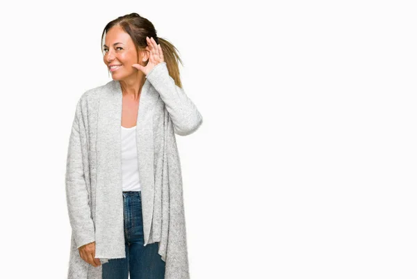 美しい中年成人女性は 噂やゴシップに審理をリスニングの耳に手を浮かべて隔離された背景に冬のセーターを着ています 難聴の概念 — ストック写真
