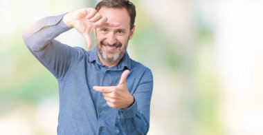 Yakışıklı orta yaş elle yapma çerçeve ve parmakları ile mutlu yüz gülümseyen izole arka plan üzerinde zarif komuta sizde. Yaratıcılık ve Fotoğrafçılık kavramı.