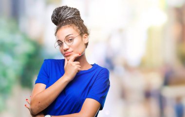 Genç saç Afro-Amerikan Kız emin çapraz kollar ve çeneme kaldırdı el ile gülümseme ile kameraya bakarak izole arka plan üzerinde gözlük takan örgülü. Pozitif düşünce.