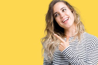 Güzel genç sarışın kadın izole arka plan neşeli üzerinde çizgili kazak giyen yüzünde mutlu ve doğal ifade ile yan yana el ve parmak ile işaret eden yüz bir gülümseme ile neşeli