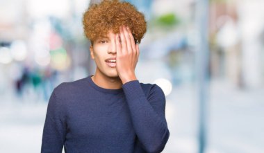 El yüz ve sürpriz duygu kendinden emin gülümseme ile tek gözüyle kapsayan afro saçlı genç yakışıklı adam.